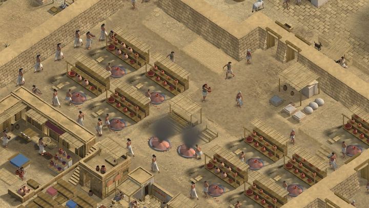 Pottery yards with drying racks full of pots and two kilns giving off smoke.